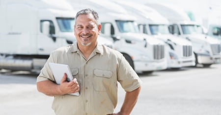 driver in front of fleet of white trucks