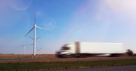 truck driving by wind turbines